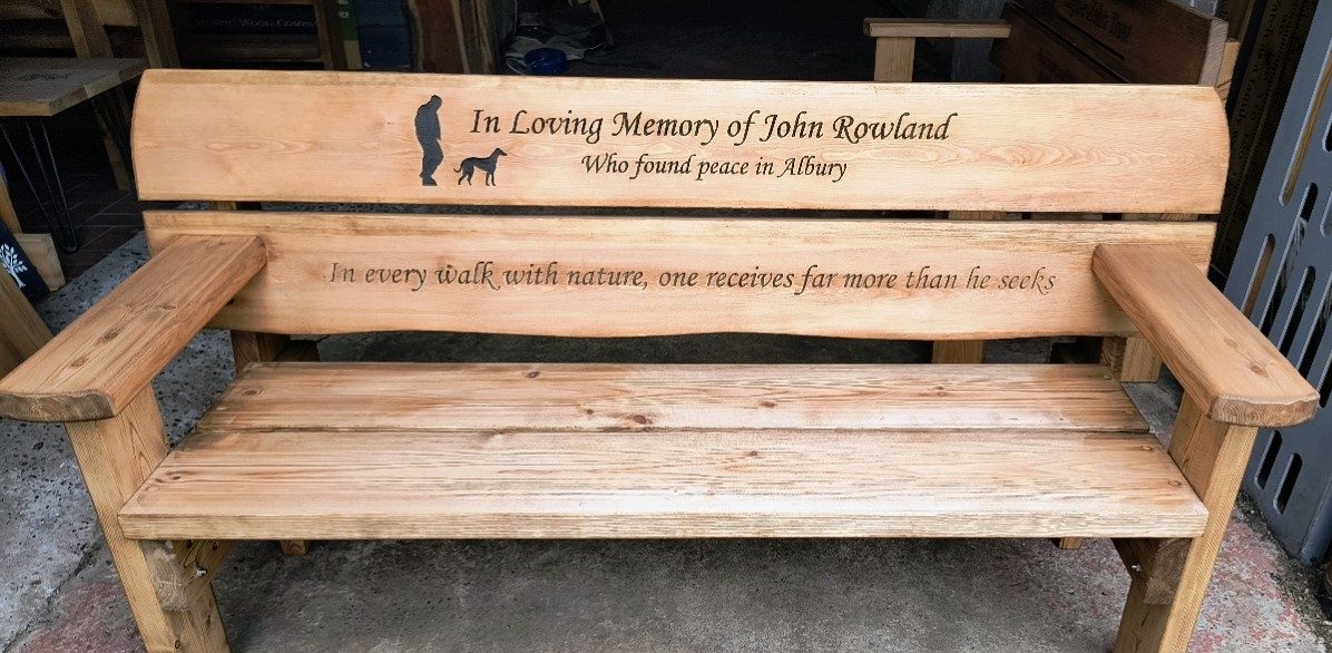Memorial bench carved with a silhouette of a man and his dog and a line about walking in nature