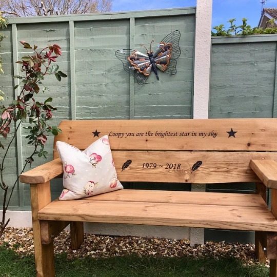 Memorial bench in a family garden with a cushion on the seat