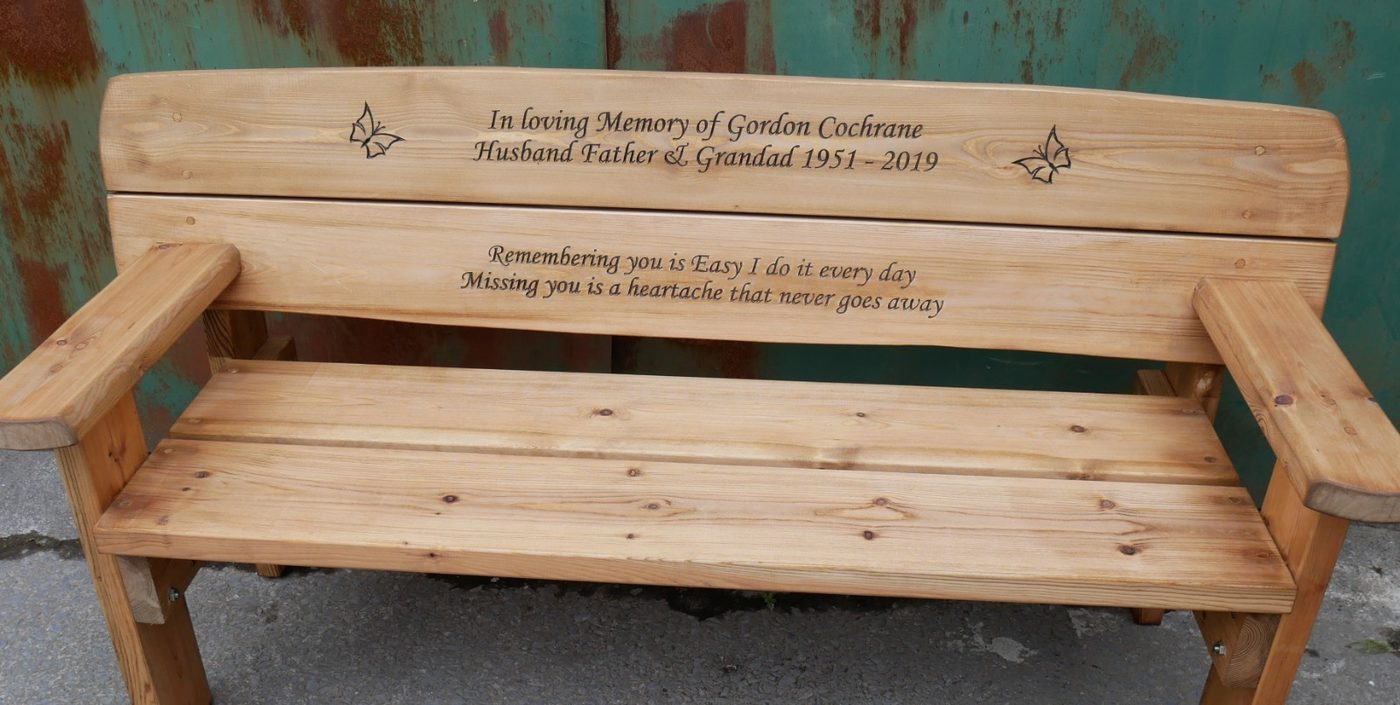 Memorial bench with carved butterflies, a name and dates